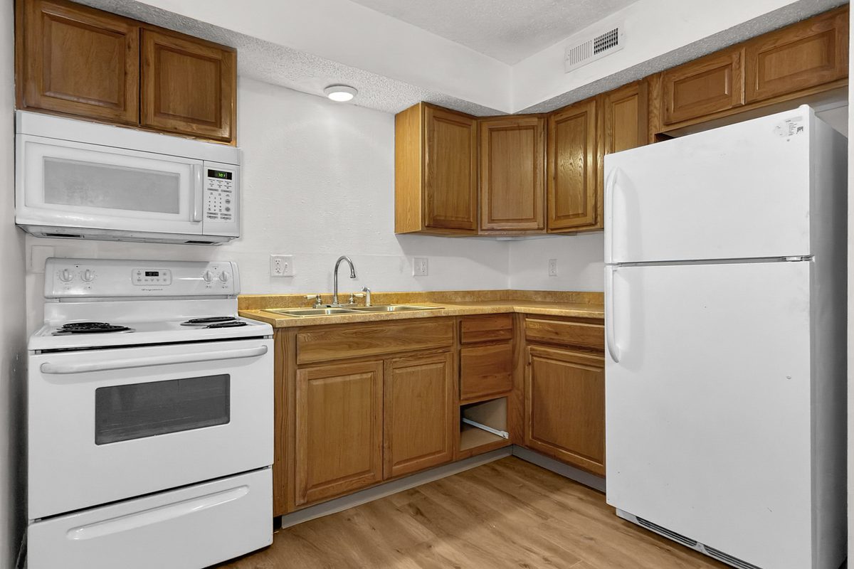 A kitchen with oak cabinets, a white range, an over-the-range microwave and a white refrigerator.